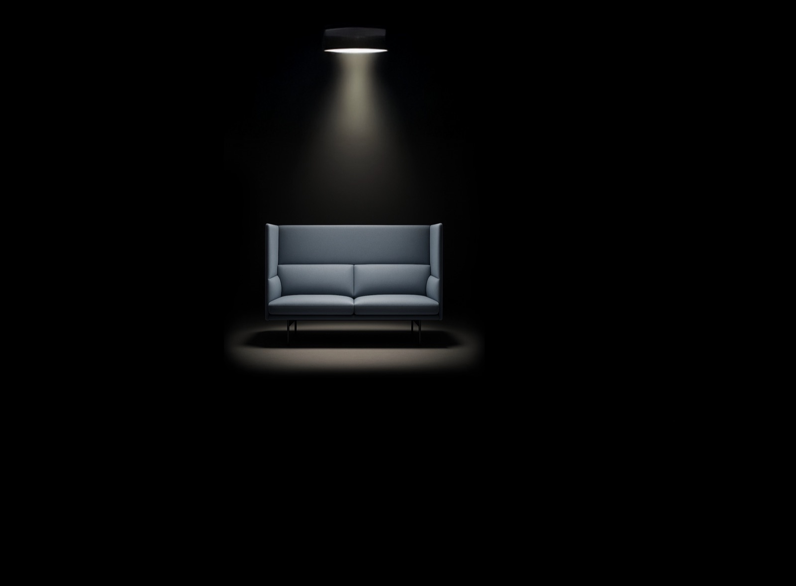 Ein Sofa allein im Lichtkegel einer Deckenlampe in einem dunklen Raum